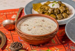 Azerbaijani Dovga soup with stuffed grape leaves
